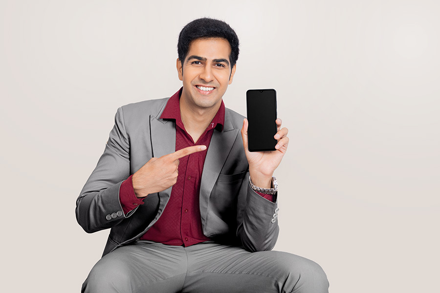 Indian businessman presenting smartphone while seated