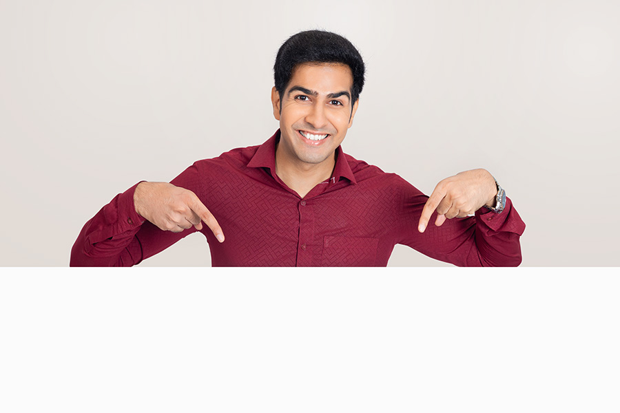 Indian man pointing downward in red shirt for copy space