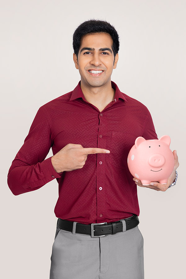 Indian man pointing at piggy bank for savings concept