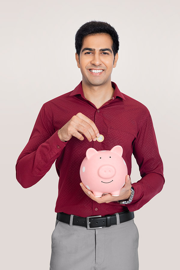 Indian businessman saving coin in piggy bank