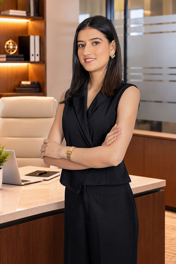 Confident female executive standing with arms crossed in modern office
