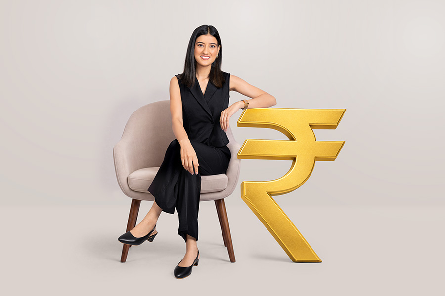 Indian businesswoman sitting beside golden rupee symbol