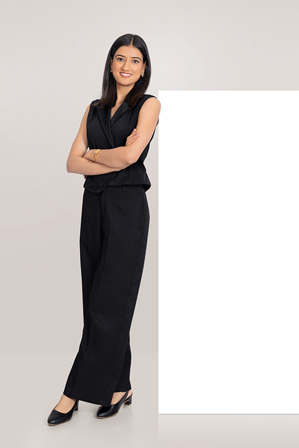 Indian businesswoman standing beside blank advertising board with arms crossed