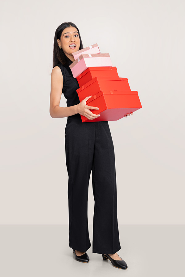 Surprised female professional carrying a stack of red and pink gift boxes