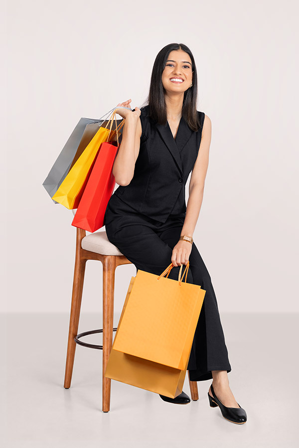 Smiling female shopper seated with colourful shopping bags