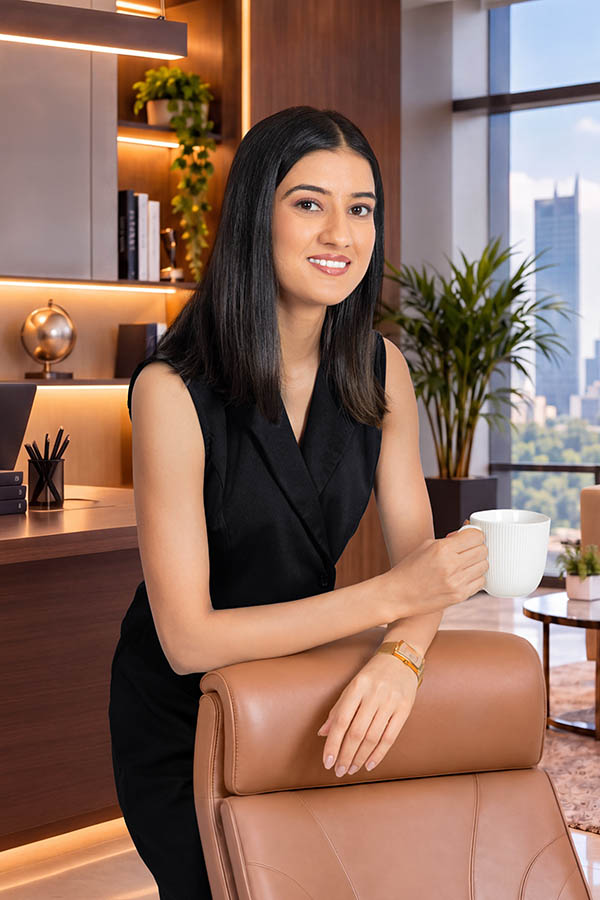 Smiling female executive holding coffee mug beside office chair