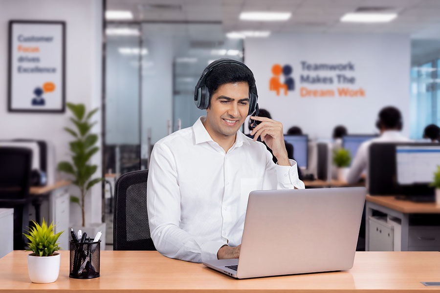 Male customer service representative speaking on headset while working on laptop