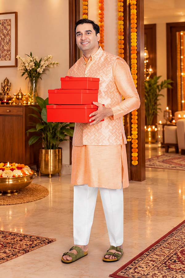 Indian man holding red gift boxes in a decorated festive home