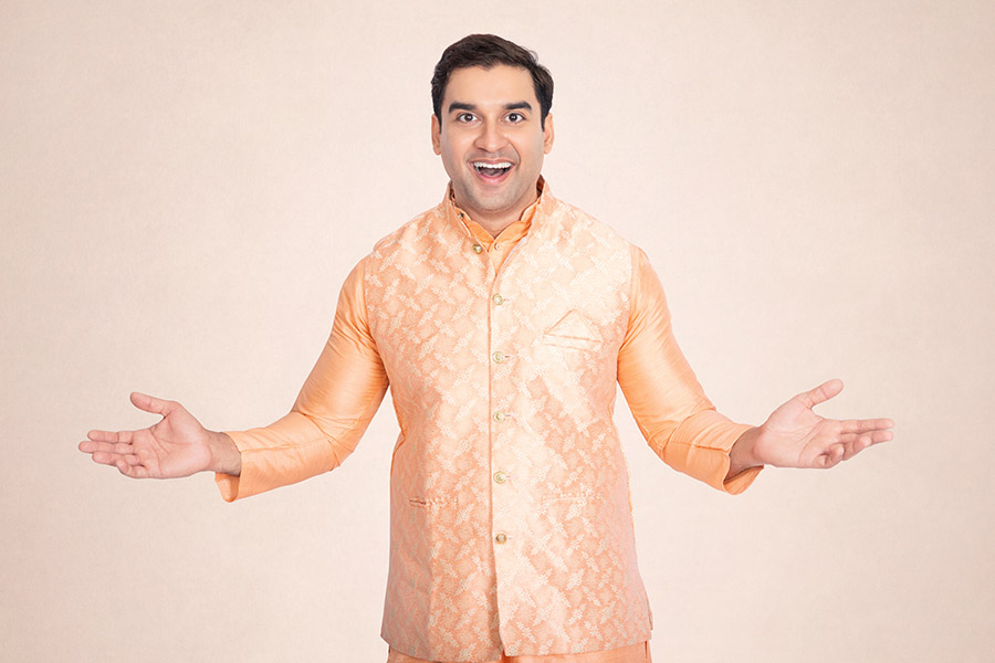 Smiling Indian man welcoming viewers in traditional peach attire