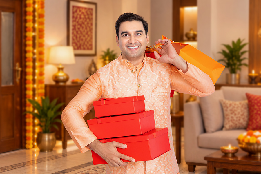 Indian man carrying red gift boxes and a shopping bag at home