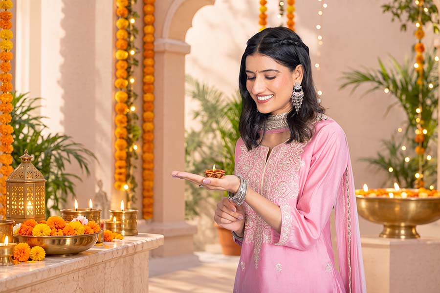 Indian woman holding a lit diya during a festive celebration