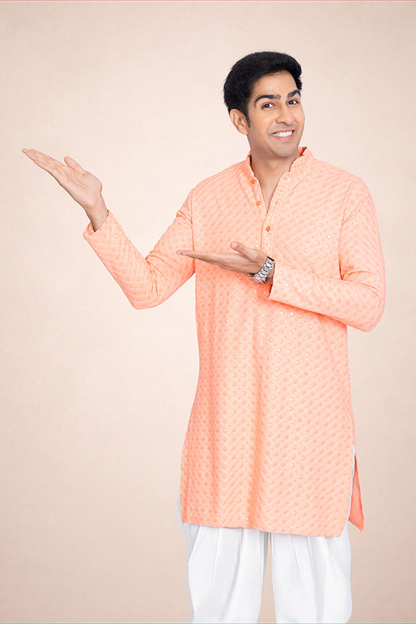 Indian man in peach kurta presenting copy space with an open palm